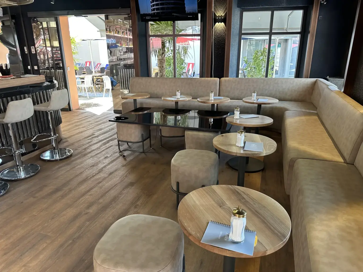Lounge-Bereich mit gepolsterter Sitzbank, runden Tischen und Barhockern